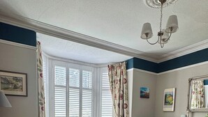 Ein Wohnzimmer mit einer Couch, einem Fernseher, einem Kamin und einem Fenster mit Vorhängen.