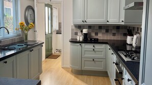 Eine Küche mit grauen Schränken, einer schwarzen Arbeitsplatte, einem eingebauten Backofen und einem Oberlicht.