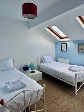Ein Schlafzimmer mit zwei Betten, einem Globus auf einem Nachttisch und einem Oberlicht.