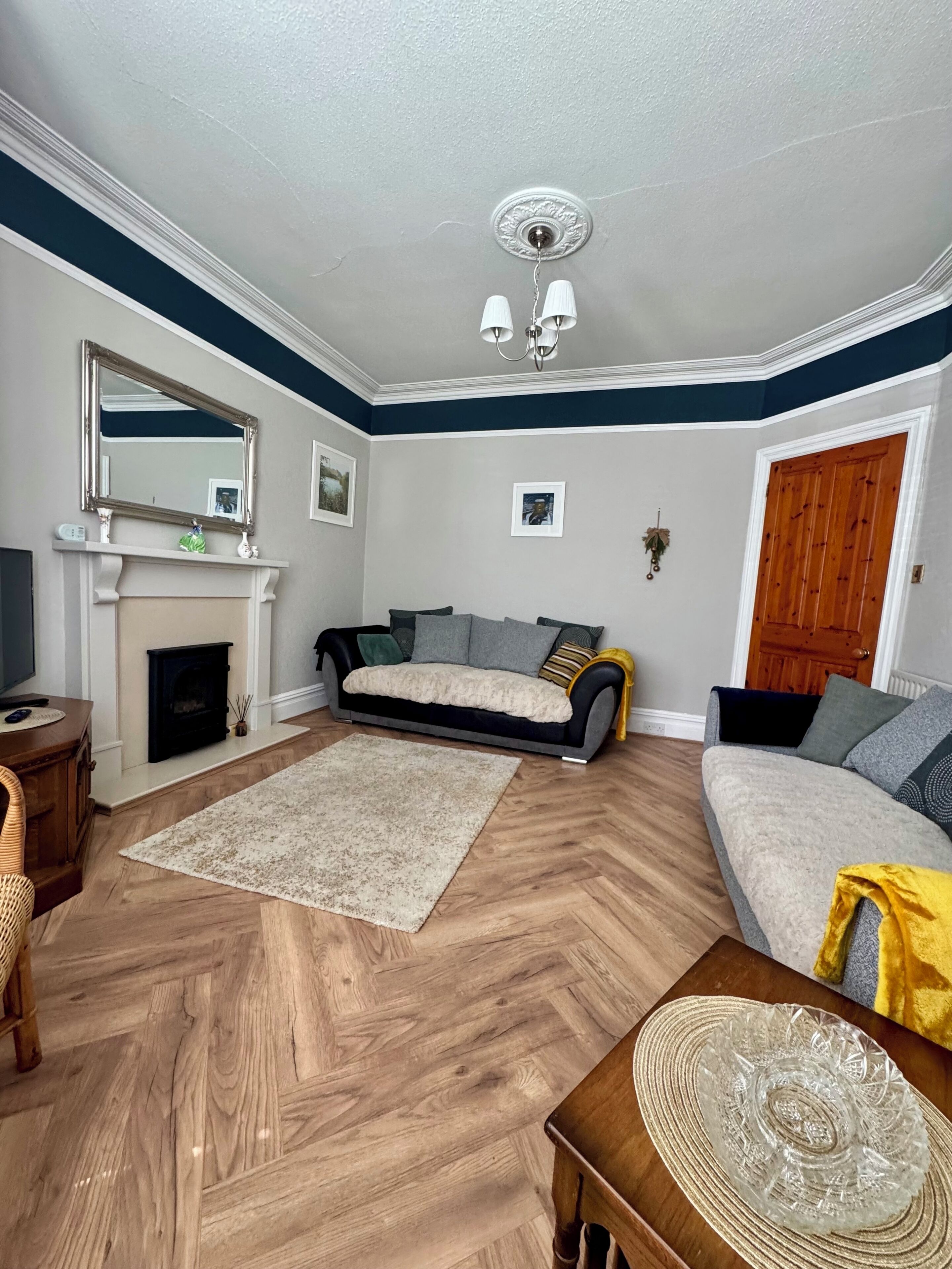 A living room with a fireplace, sofa, and wooden flooring.