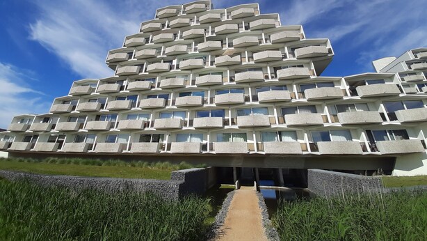A modern, multi-story building with a unique architectural design featuring numerous balconies.