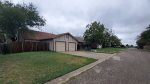 A residential street with houses, a driveway, and a grassy lawn. - Home in NW Austin 2 BR 2 BA Private Parking Private Patio Pet Stays for Free ! (Austin)