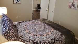 A bedroom with a bed, a bedside lamp, a door, and a wall clock. - Home in NW Austin 2 BR 2 BA Private Parking Private Patio Pet Stays for Free ! (Austin)