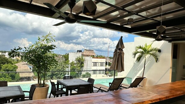 A rooftop terrace with a pool, lounge chairs, and a wooden bar. - Moonshine Tulum Hotel  (Tulum)