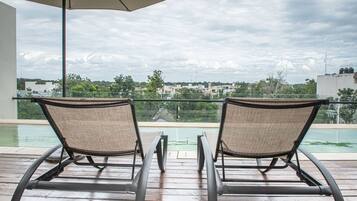 Una piscina al aire libre, sillones reclinables de piscina