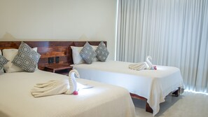 A hotel room with two beds, each with a swan towel, patterned pillows, and a wooden headboard. - Moonshine Tulum Hotel  (Tulum)