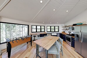 A modern kitchen with a wooden table, bar stools, and a foosball table.