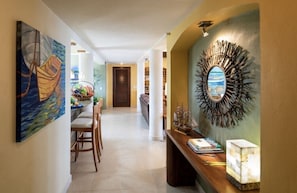 A hallway with a dining area, a decorative mirror, and a view of the ocean.