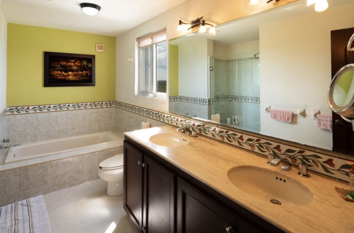 Une salle de bain avec une baignoire, deux lavabos, des toilettes, un grand miroir et une douche.