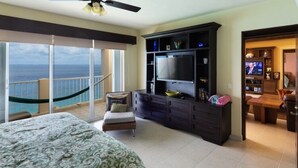 A spacious bedroom with a large bed, a TV, and a balcony with a view of the ocean. - Cozumel Penthouse Condo-Las Brisas 702 (San Miguel de Cozumel)