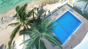 A beach view with clear turquoise water, a pool, and palm trees. - Cozumel Penthouse Condo-Las Brisas 702 (San Miguel de Cozumel)