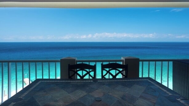 A balcony with a view of the ocean, a table, and two chairs. - Cozumel Penthouse Condo-Las Brisas 702 (San Miguel de Cozumel)