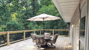 Une terrasse en bois avec une table et des chaises, un parasol et une rambarde.