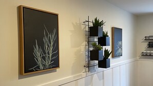 A hallway with framed artwork on the walls, a plant shelf, and a radiator. - Newly renovated1 Bedroom 1 Bath in the Heart of Downtown Ellsworth.  (Ellsworth)