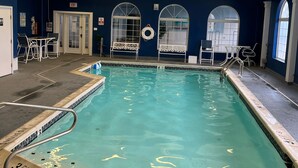 Une piscine intérieure à l’eau claire, avec un panneau indiquant qu’il est interdit de plonger et une bouée de sauvetage fixée au mur.