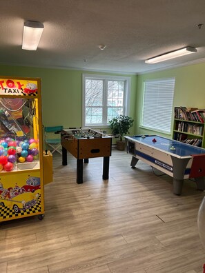 Une salle de loisirs équipée d’un baby-foot, d’une table de billard et d’une machine de jeu où l’on peut attraper des jouets à l’aide d’une pince.