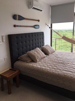 A bedroom with a large bed, a headboard, a hammock, and two paddles on the wall.