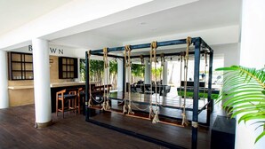 A spacious indoor area with a wooden floor, a seating area with tables and chairs, and a rope swing structure. - OCEAN VIEW APARTMENT (Dzemul,)