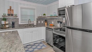 A modern kitchen with white cabinets, stainless steel appliances, and a granite countertop. - Peach Beach Retreat-Restored Rustic Gem- 3BR 1.5B (Murrells Inlet)