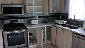 A modern kitchen with stainless steel appliances, wooden cabinets, and a window providing natural light. - Detached 3 BR home in Ajax,ON (Ajax)