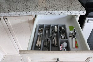Eine Küchenschublade mit Besteck und einem grünen Pfannenwender.