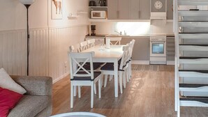 A compact kitchen with white appliances, a dining area with white chairs, and a wooden floor. - Cozy home in Sysslebäck with kitchen (Sysslebäck)