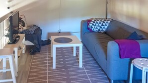 A living room with a sofa, a small table, a TV, and a patterned rug. - Cozy home in Sysslebäck with kitchen (Sysslebäck)