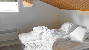 A neatly made bed in a room with a sloped ceiling and a circular window. - Cozy home in Sysslebäck with kitchen (Sysslebäck)