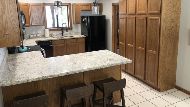 A kitchen with wooden cabinets, a granite countertop, a black refrigerator, and a window with a view. - Cozy mountain retreat at 7,200 feet. - Sleeps 9 (Pinetop)