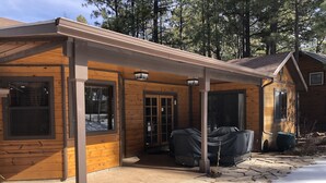 A wooden cabin with a covered porch, stone steps, and a covered outdoor seating area. - Cozy mountain retreat at 7,200 feet. - Sleeps 9 (Pinetop)