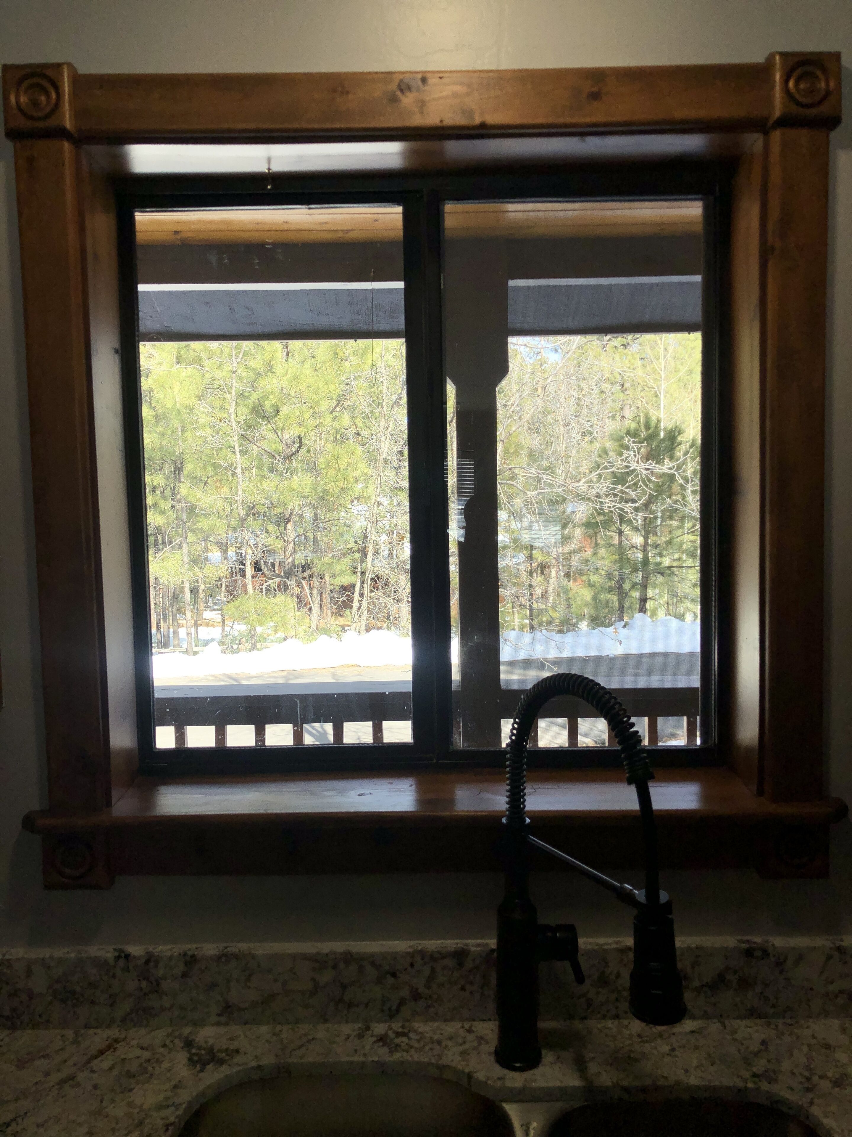 A kitchen with a window overlooking a snowy landscape and trees.