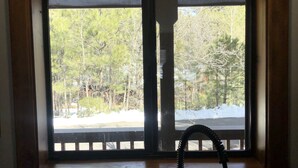 A kitchen with a window overlooking a snowy landscape and trees. - Cozy mountain retreat at 7,200 feet. - Sleeps 9 (Pinetop)
