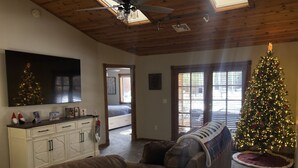 A living room with a brown leather sofa, a white cabinet, a Christmas tree, and a flat-screen TV mounted on the wall. - Cozy mountain retreat at 7,200 feet. - Sleeps 9 (Pinetop)