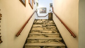 A marble staircase with wooden handrails, leading to a landing with framed pictures on the wall. - 3 bedroom pet friendly home in Piombino (Piombino)