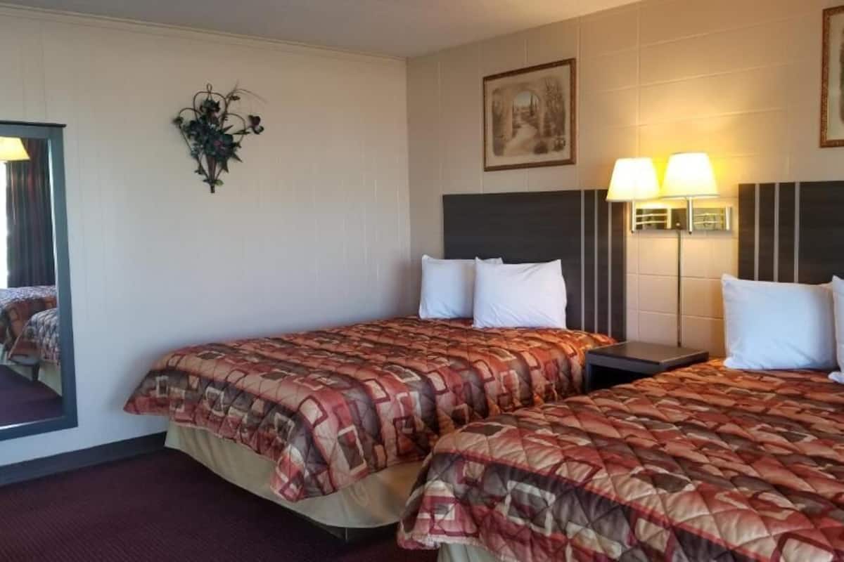 Ein Hotelzimmer mit zwei Betten, einem großen Spiegel und zwei Wandlampen.
