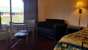 Een hotelkamer met een bed, een bureau met stoel, een bank en een lamp.