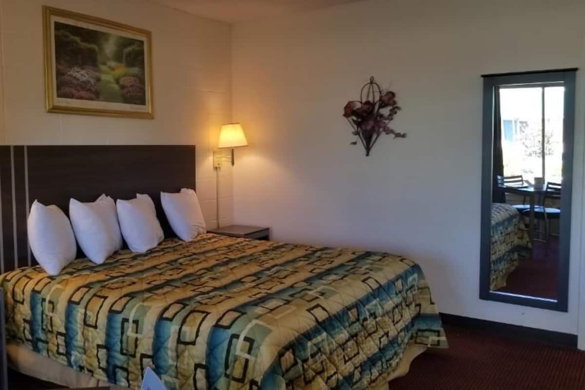 Ein Hotelzimmer mit einem großen Bett, zwei Nachttischlampen, einer Wanddekoration mit Blumen und einem Bild über dem Bett.