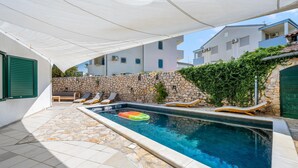 Una piscina con lettini e un muro in pietra.