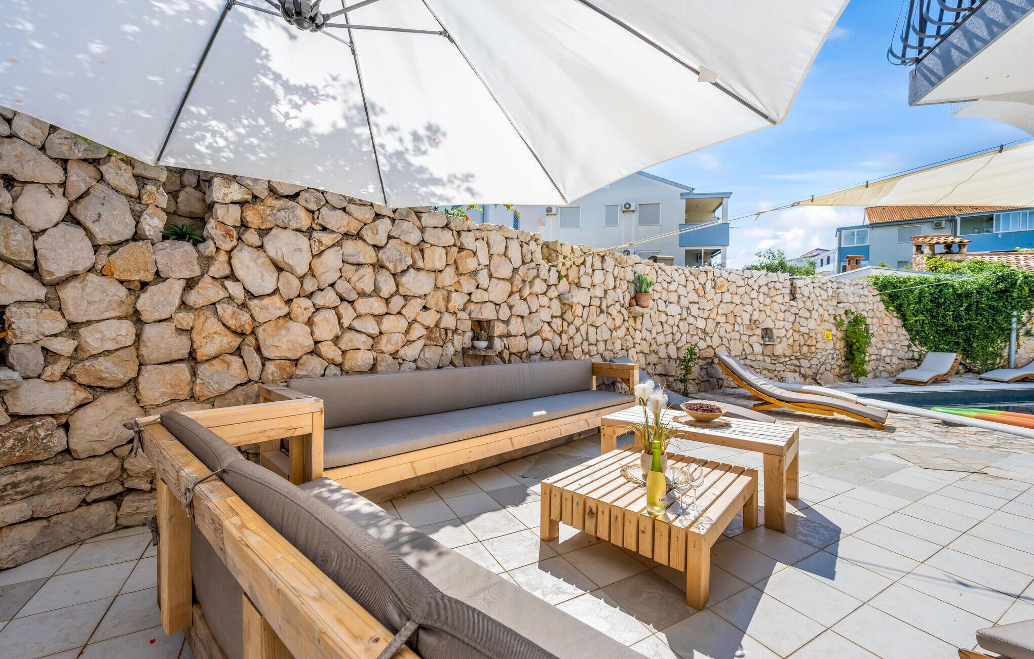 A stone wall, wooden furniture, and a pool area.