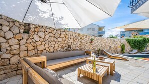 Un muro in pietra, mobili in legno e una zona piscina.