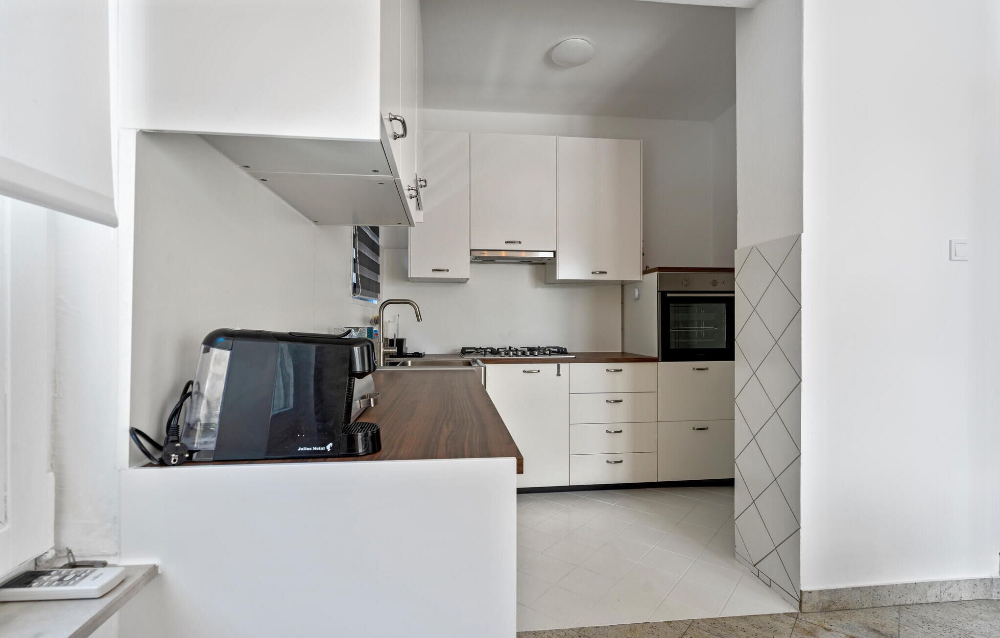 A modern kitchen with white cabinets, a built-in oven, and a stove.