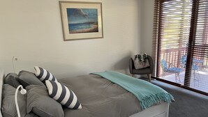 Una camera da letto moderna con un letto, cuscini, una lampada da comodino, una coperta e un quadro appeso al muro.
