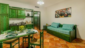 Een kamer met groen meubilair, een eettafel voor vier personen en een bank met decoratieve kussens.