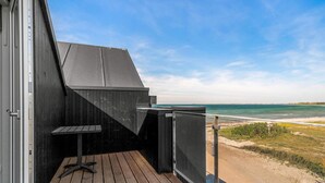 En træterrasse med udsigt over havet og en strand.