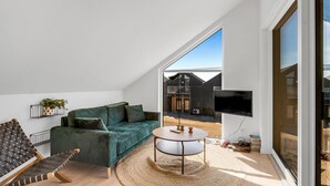 En moderne stue med en grøn sofa, et rundt sofabord og et fjernsyn.
