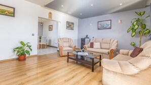 Un salon spacieux doté d’un parquet, de canapés beiges, d’une table basse en verre et d’un coin repas avec des chaises et une table.