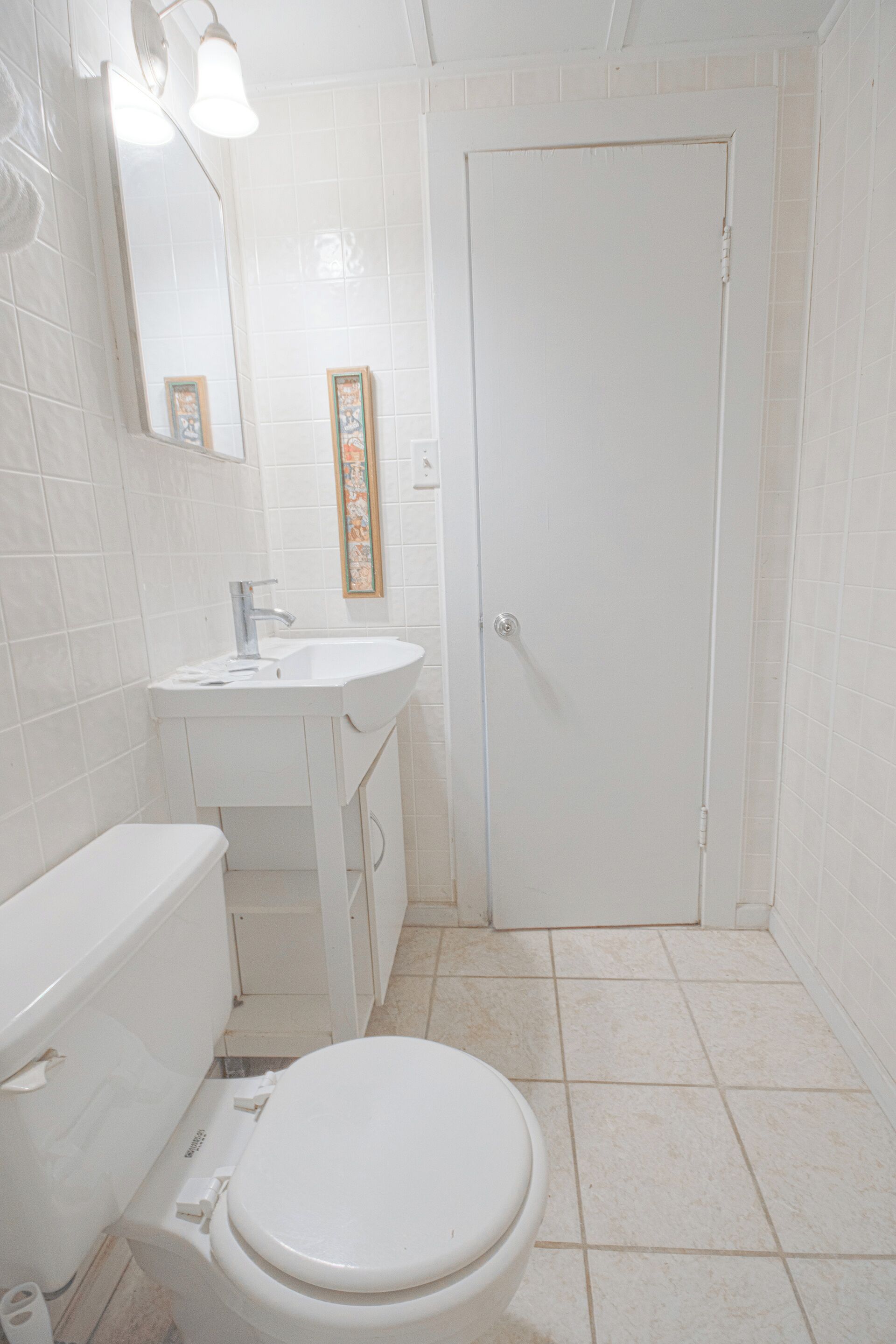 A bathroom with a toilet, sink, and mirror.