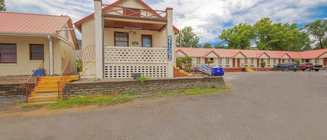 A motel with a red roof, a welcome sign, and a blue sign indicating an office.
