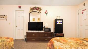A hotel room with a bed, a dresser, a television, a microwave, and a refrigerator.
