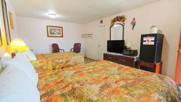 A hotel room with two beds, a desk, a chair, a TV, and a refrigerator.